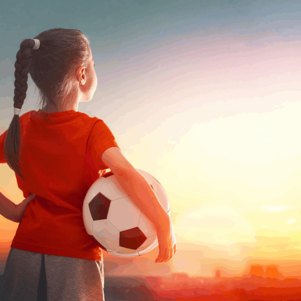 Enfant avec ballon de football regardant l'horizon au coucher du soleil, symbolisant l'enfant Manifesteur en Design Humain